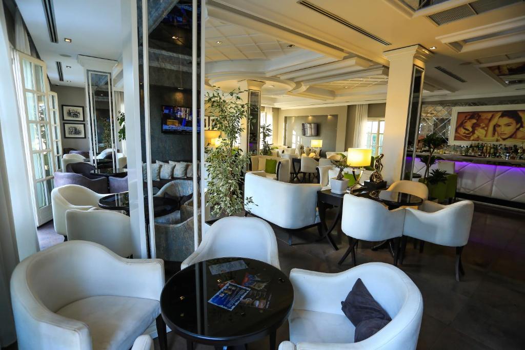 a restaurant with white chairs and tables and a mirror at Hotel Monarch in Elbasan