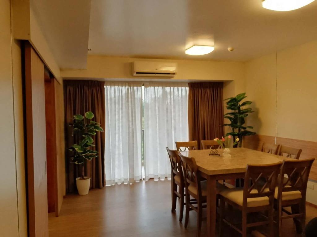 Luntian Luxury Condo in Tagaytay في Iruhin: غرفة طعام بها طاولة وكراسي ونافذة