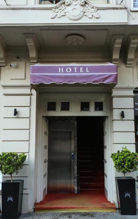 a hotel entrance with a purple awning and two plants at Hotel Monarch in Elbasan
