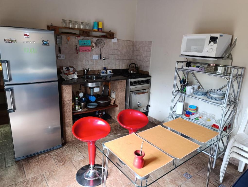 a kitchen with a stainless steel refrigerator and red stools at Complejo Terracota Quilmes in Ezpeleta