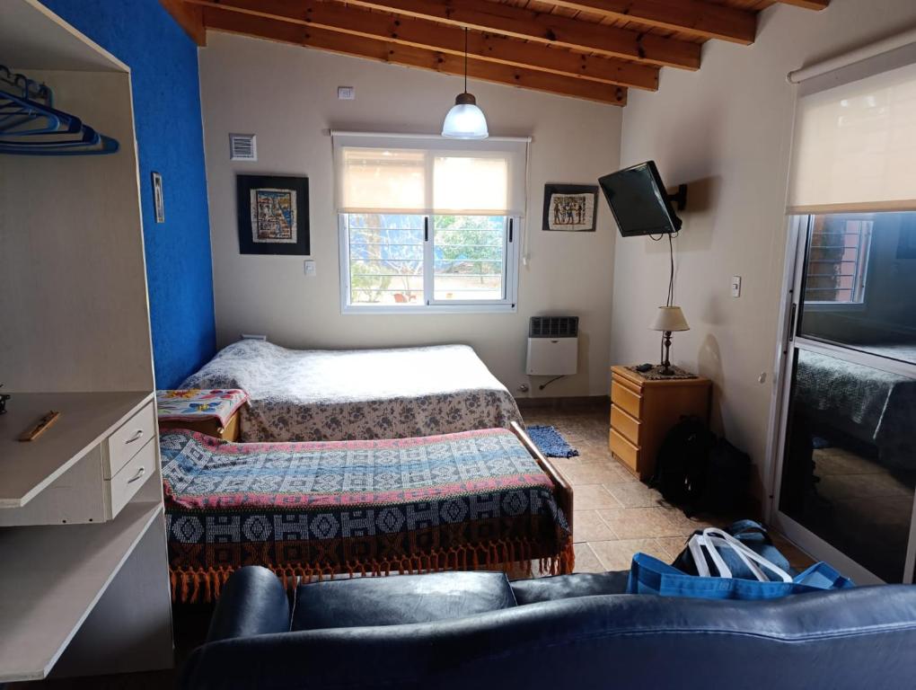 ein Schlafzimmer mit einem Bett, einem Fernseher und einer Couch in der Unterkunft Complejo Terracota Ezpeleta in Ezpeleta