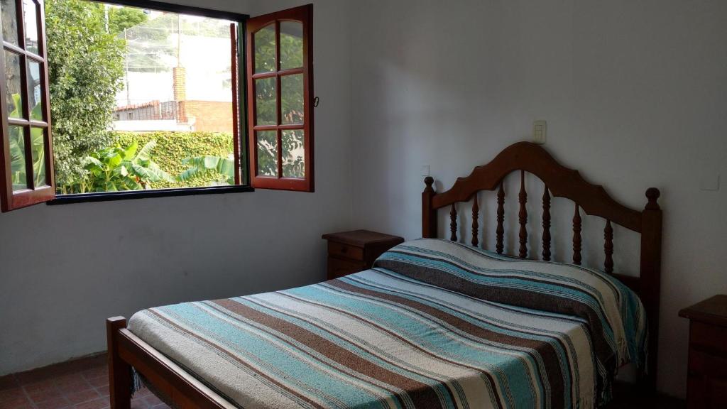 una camera da letto con un letto con una coperta a righe e due finestre di Complejo Zara a Villa Carlos Paz
