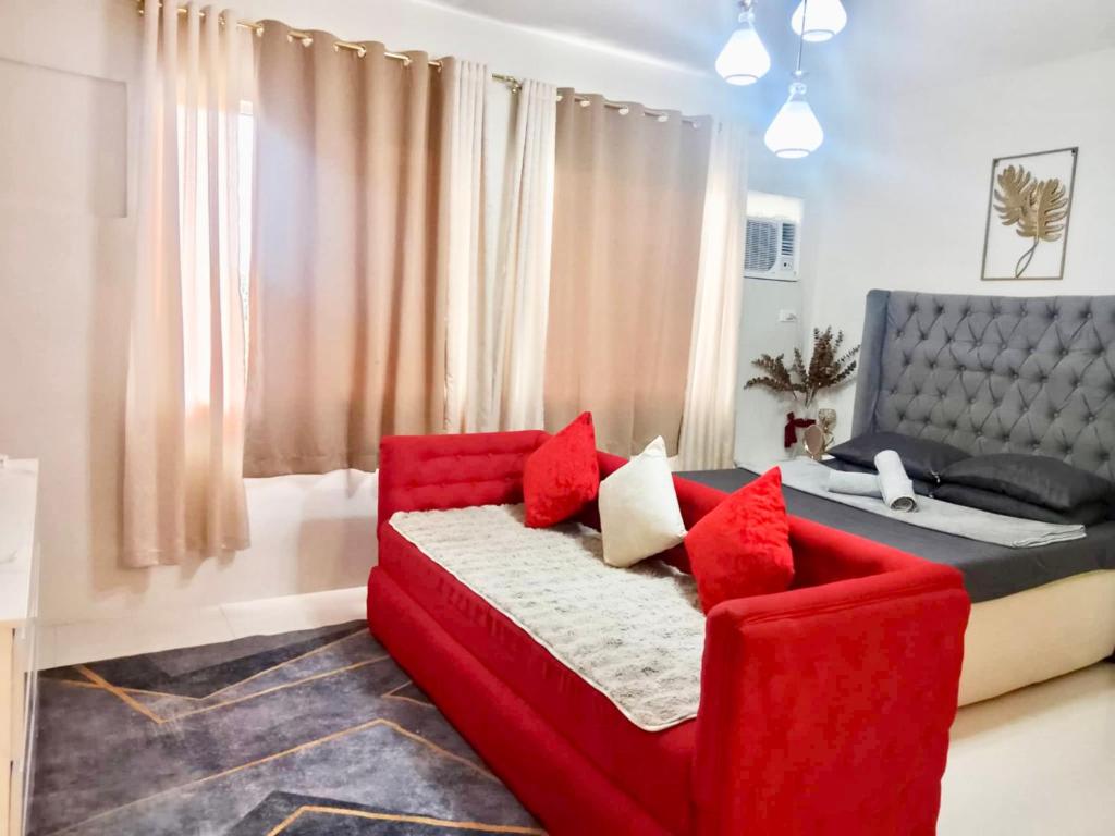un soggiorno con divano rosso e letto di spacious condo at camella manors unit 5m a Bacolod