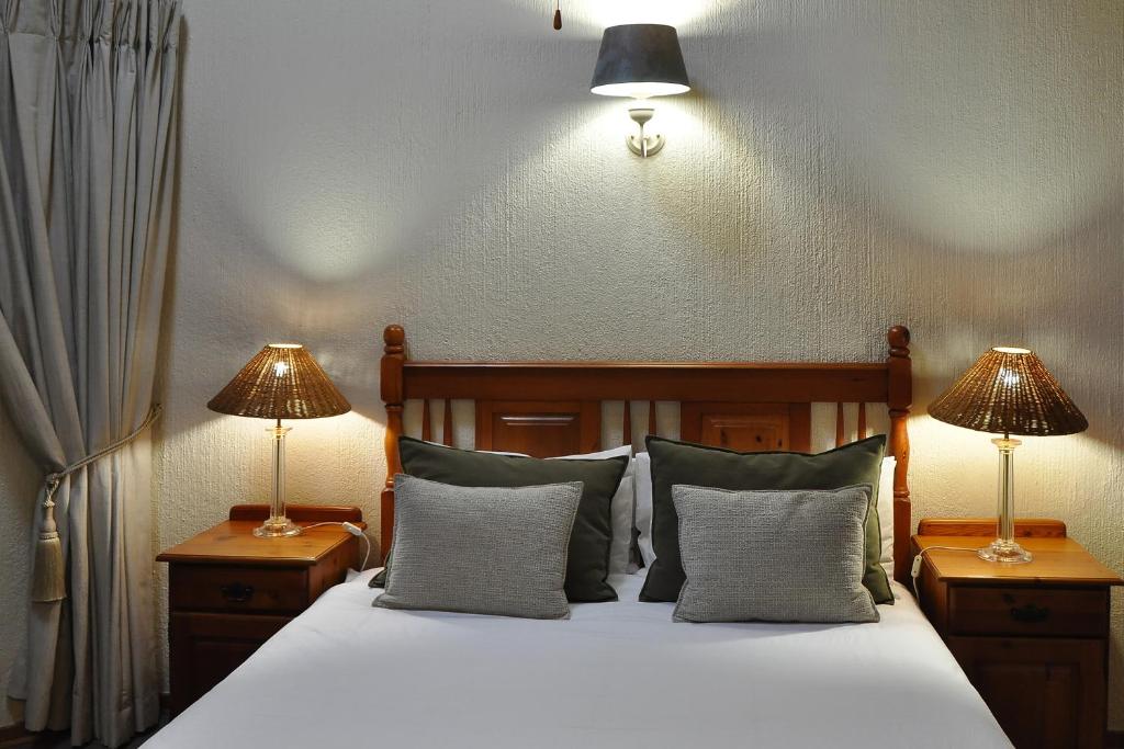 a bedroom with a bed with two lamps on tables at Kruger Park Lodge Unit No. 543 in Hazyview