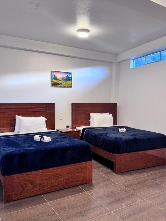 MancosLos Angeles Alojamiento的房间里有两张铺着蓝色床单的床