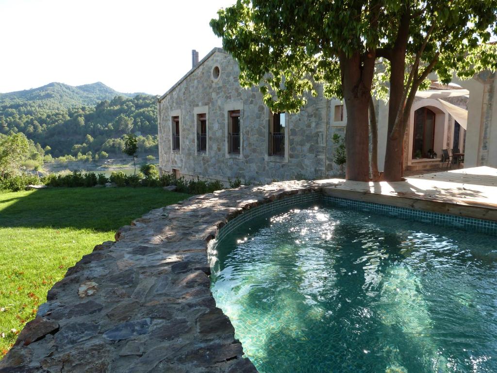 a swimming pool with a tree and a house at Casa Vella del Panta in Ríudecañas