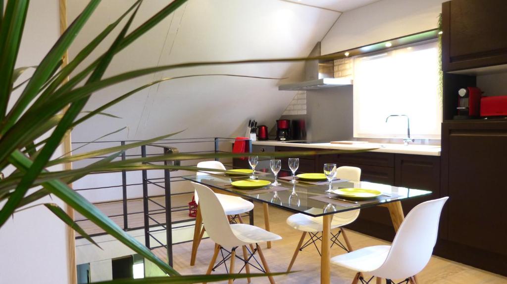 a dining room with a glass table and white chairs at Millygite Cosy Loft in Milly-la-Forêt