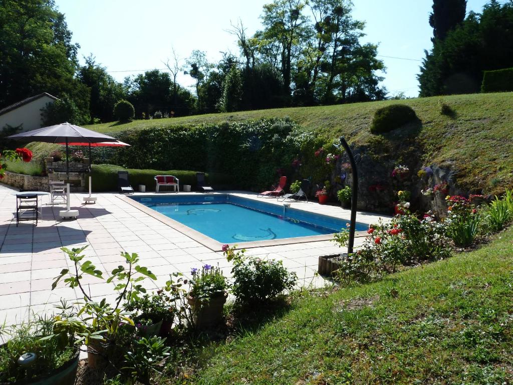 a swimming pool in a garden with a hill at En Rouge et Noir in Monbazillac