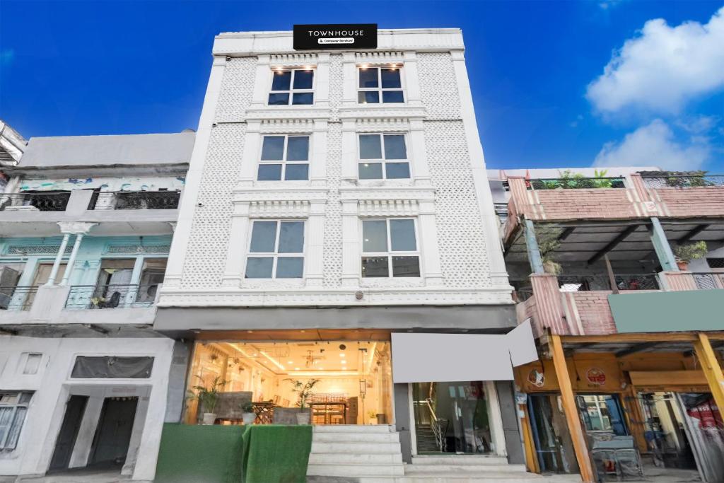 Super Townhouse Kali Ghat Prayagraj Formerly Ramesh Palace في Prayagraj: مبنى أبيض طويل عليه علامة