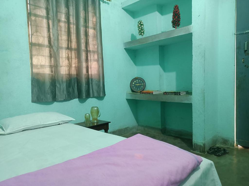 a bedroom with a bed and a clock on a shelf at santosh lodge in Muzaffarpur