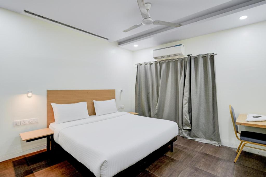 a bedroom with a white bed and a desk at Hotel Heaven Luxes Opp Miraj Cinemas in Hyderabad