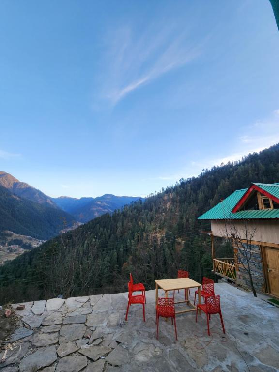 a table and chairs on a patio with a view at Winterfell Cottages - Edition Tandi in Jibhi