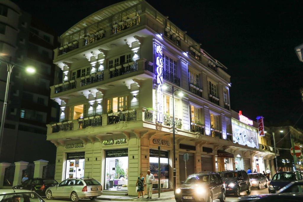 a building with a neon sign on the side of it at Hotel Monarch in Elbasan