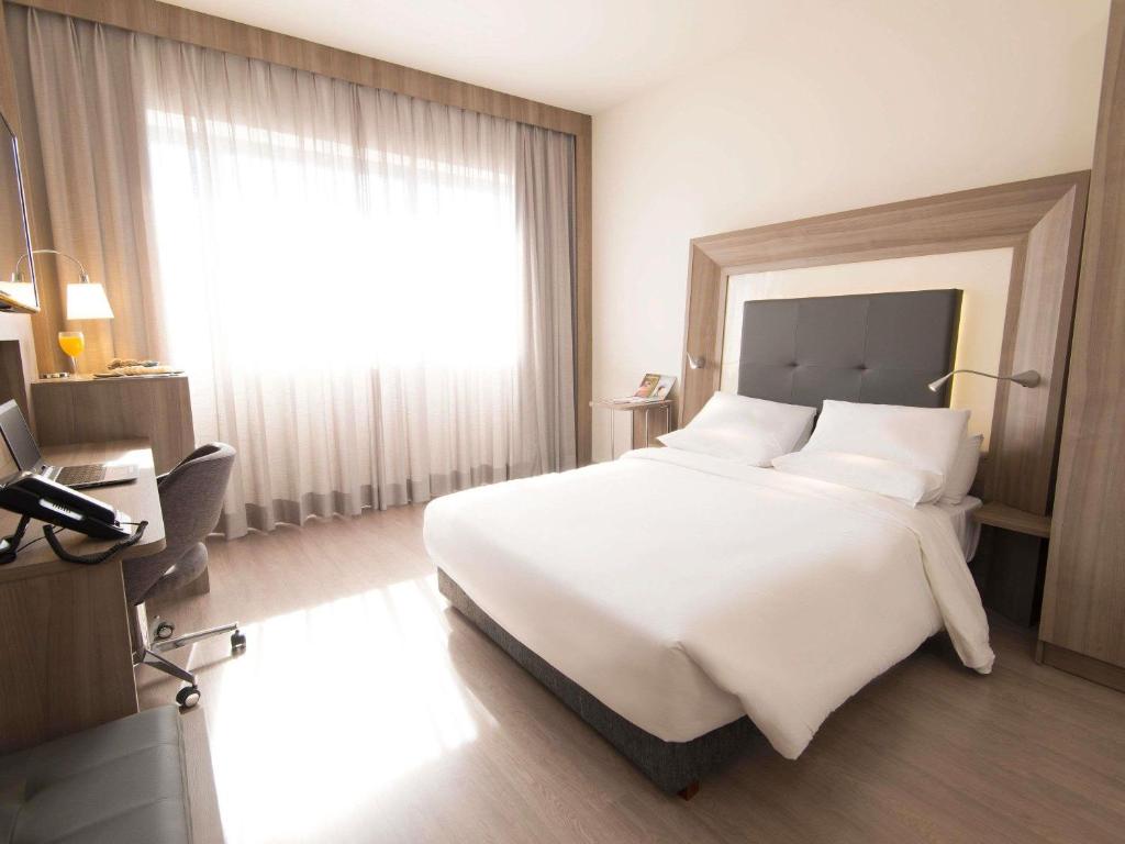 Un dormitorio con una cama blanca grande y una ventana en Novotel São Paulo Berrini, en São Paulo