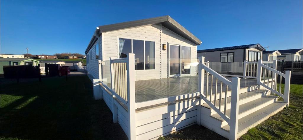 a white house with a deck on the grass at Bay View Lodge in Heysham
