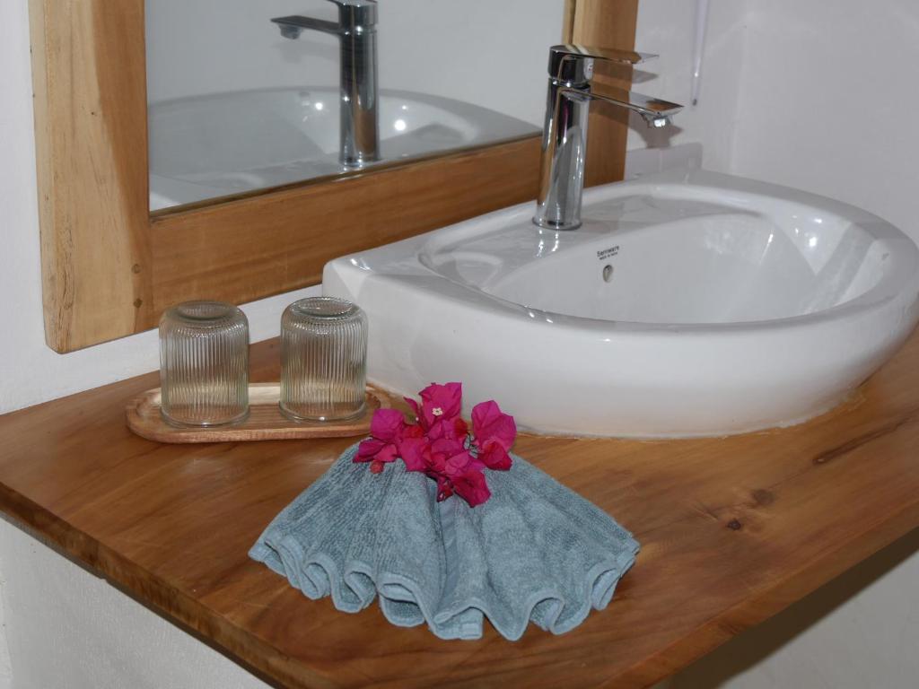 een wastafel met een bloem op een houten aanrechtblad bij Palm House&Restaurant in Utende