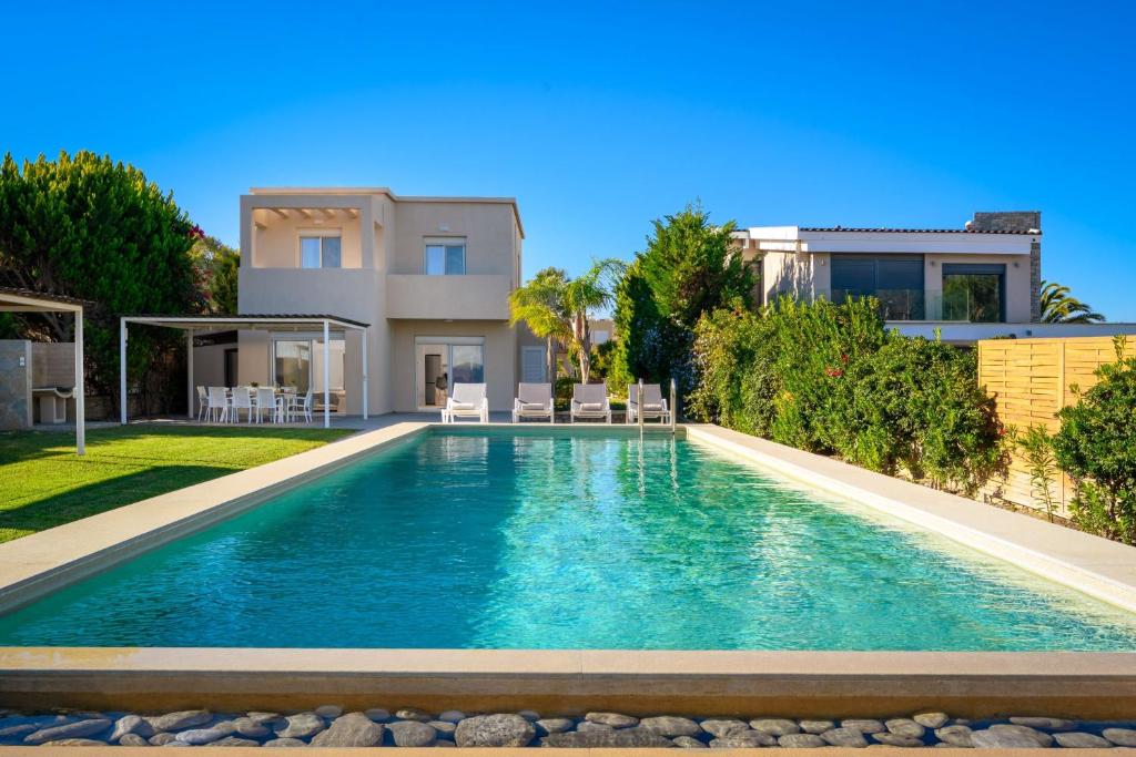 a villa with a swimming pool in front of a house at Sea Homes Villas-Villa Sylvia in Kiotari