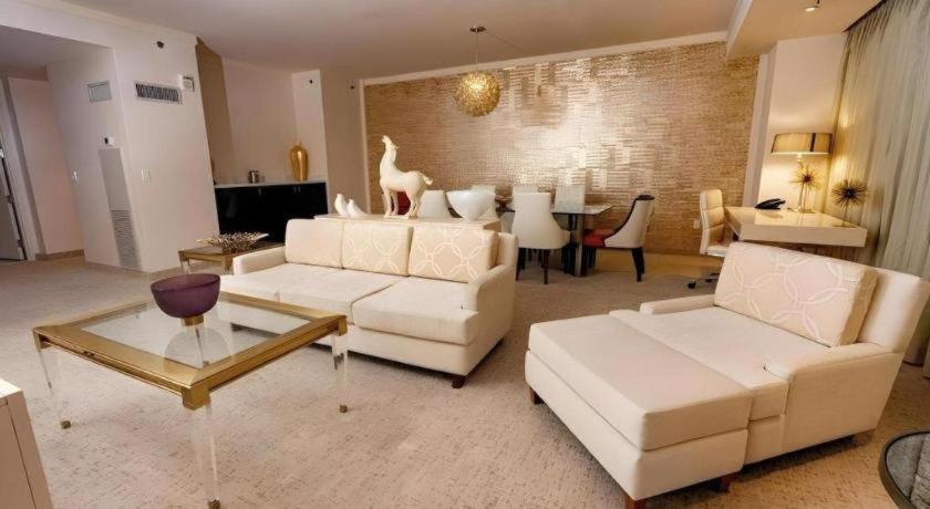 a living room with white couches and a dining room at Ahern Hotel and Event Center in Las Vegas