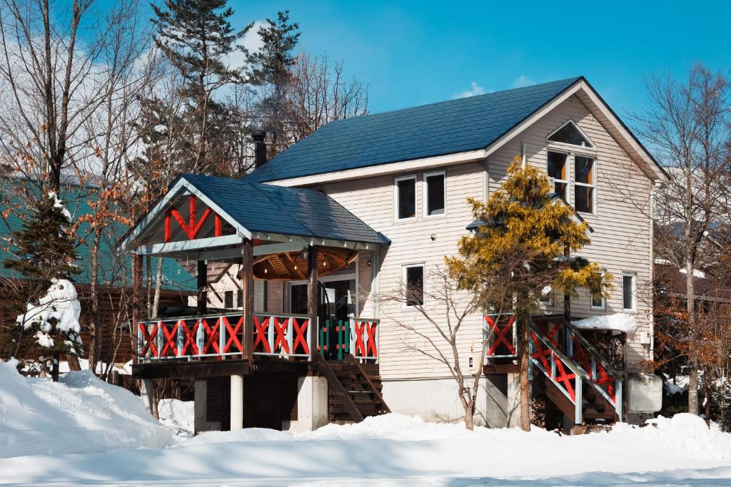 a white house with a porch in the snow at Chalet GOROU in Hakuba
