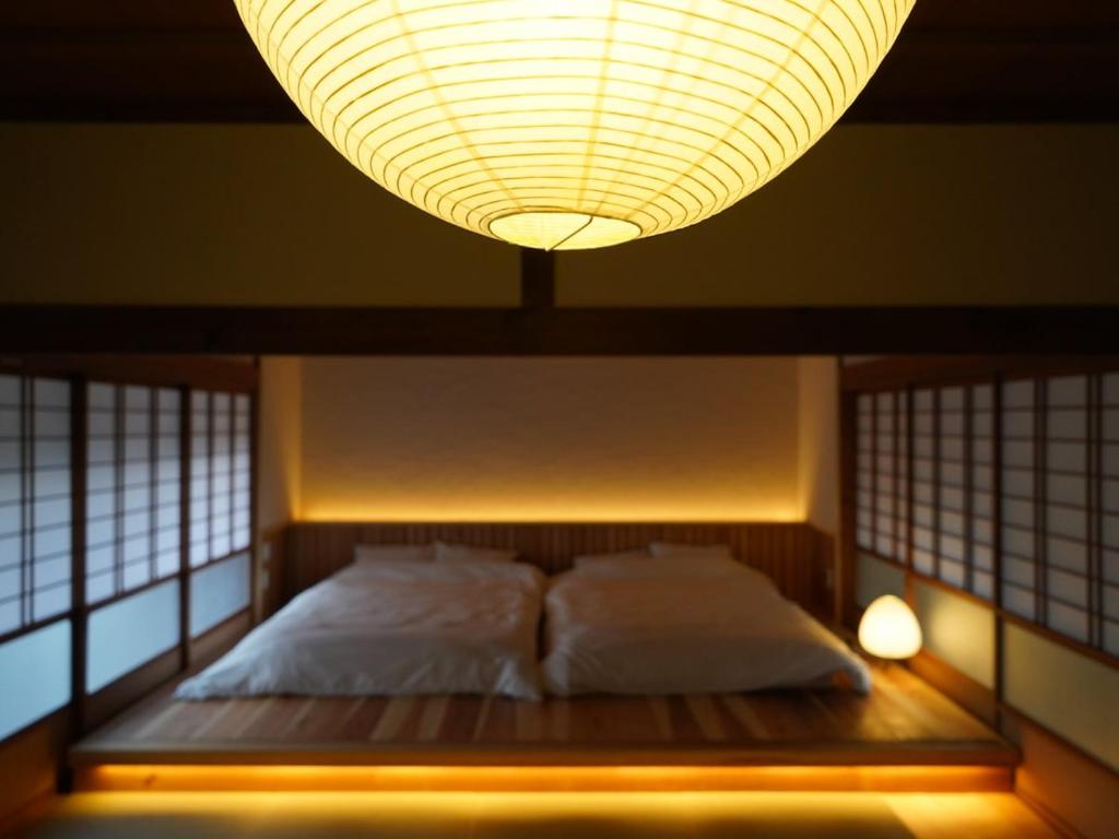 a bedroom with a bed with a large chandelier above it at Newopen 一棟貸切宿YUNOWA 車3台駐車可 6名様まで同料金 in Nagato