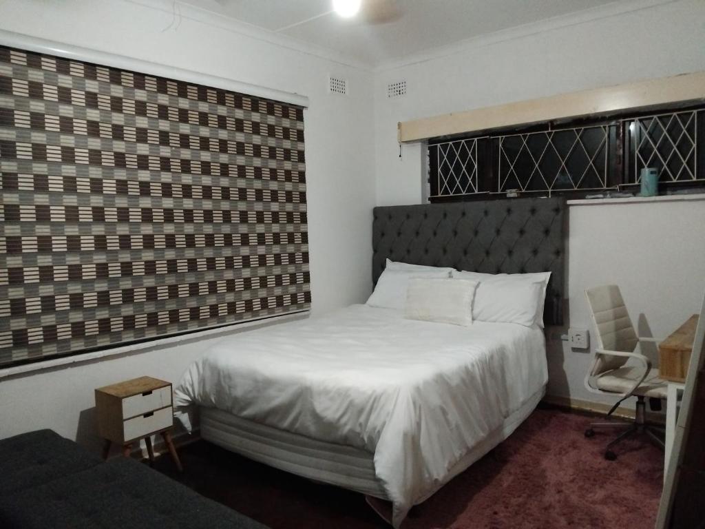 Un dormitorio con una cama blanca y una silla. en SoloGracia, en Port Edward