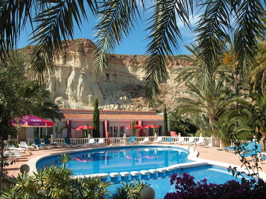 a swimming pool with a mountain in the background at Apartamentos Oasis de las Palmeras in Bolnuevo