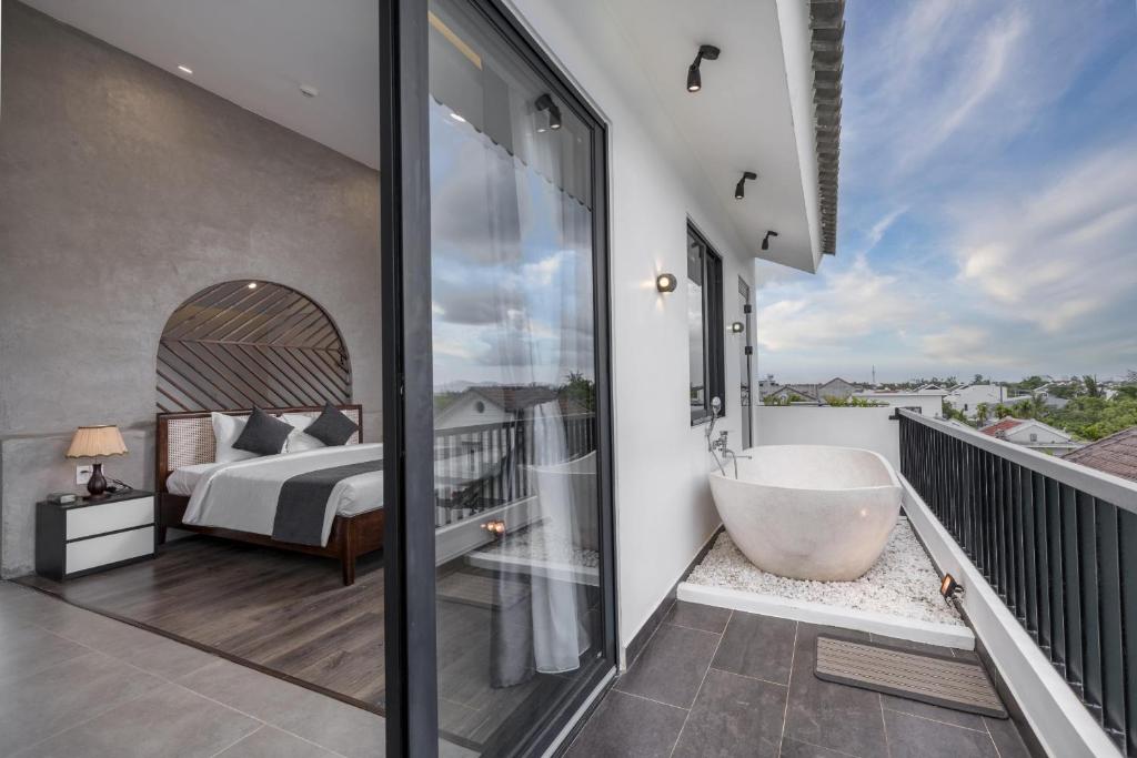 um quarto com uma banheira e uma cama numa varanda em Anchie Retreat Villa Hội An em An Bàn (2)