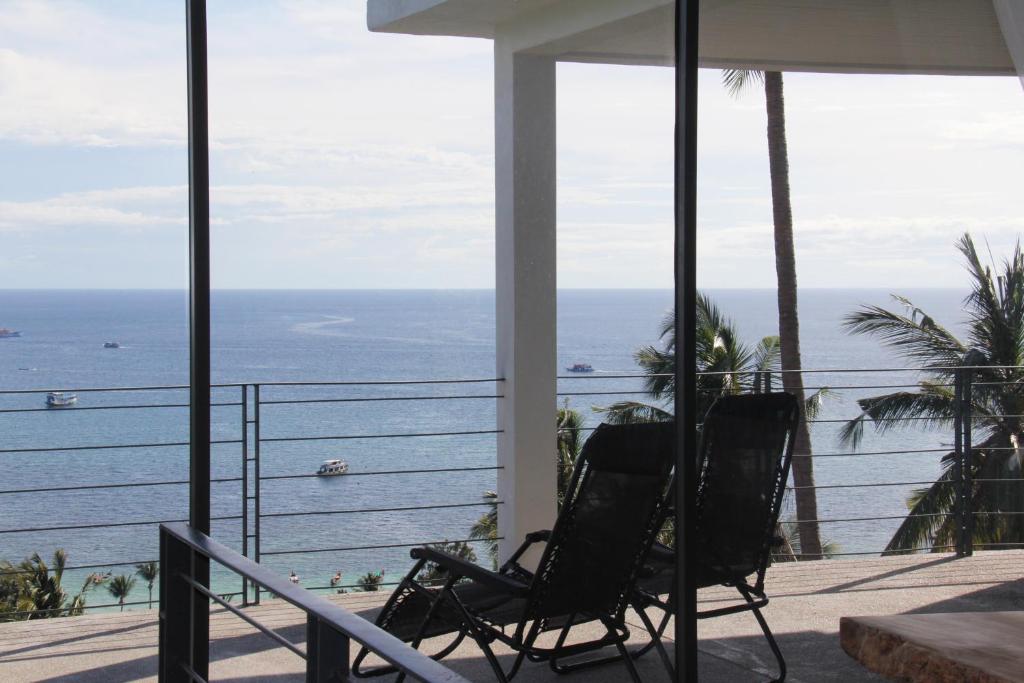 - deux chaises assises sur un balcon donnant sur l'océan dans l'établissement Anankhira Villas, à Koh Tao