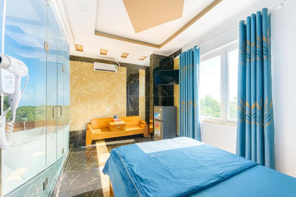 Khách Sạn Khánh Bình - Bình Dương في Tân Uyên: غرفة نوم مع حوض استحمام وسرير ودش