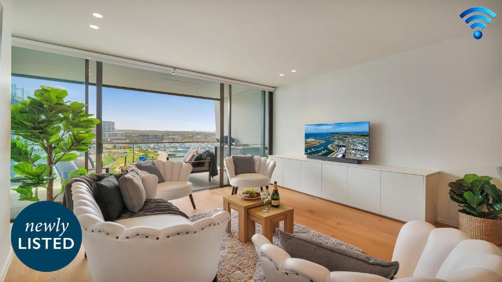een woonkamer met witte meubels en een televisie bij Marina Belle in Shellharbour