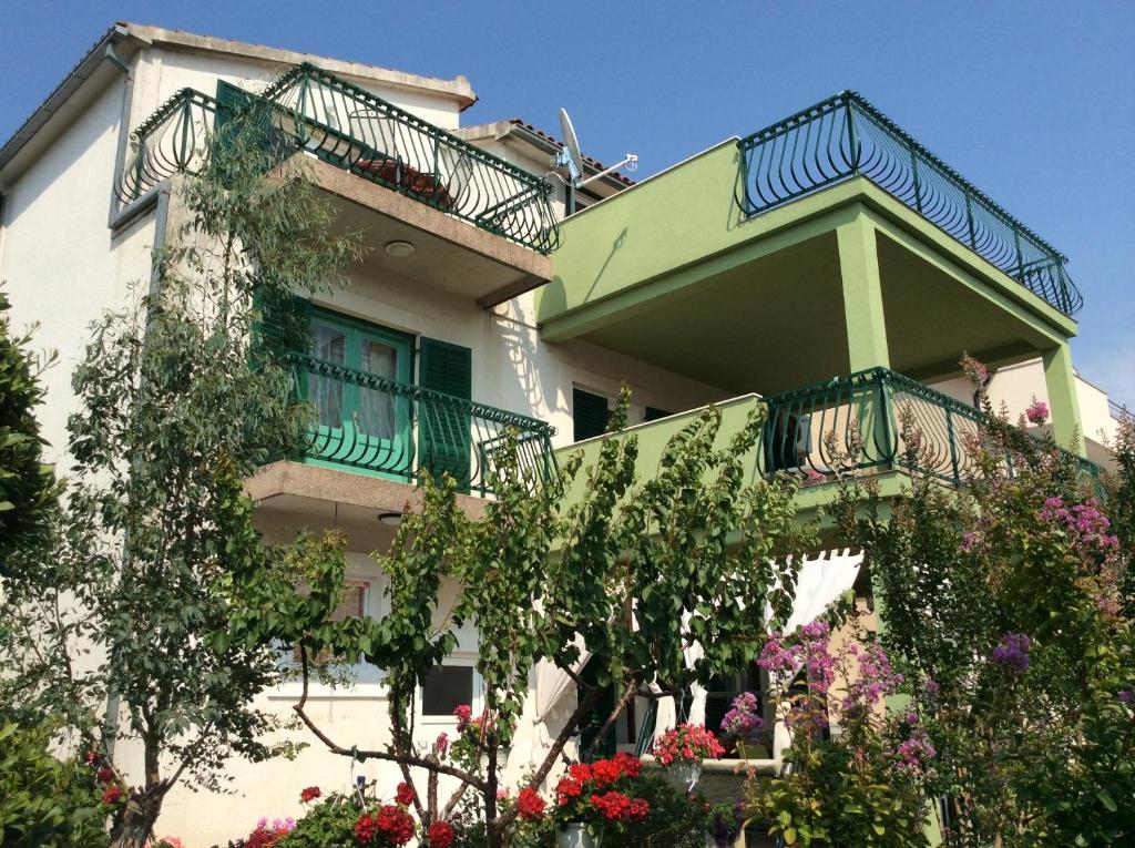 a building with a balcony and flowers in front of it at Apartmani Agard in Brodarica