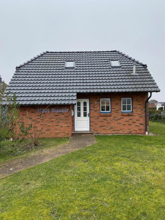 a brick house with a white door in a yard at Haus Blaubär in Friedrichskoog
