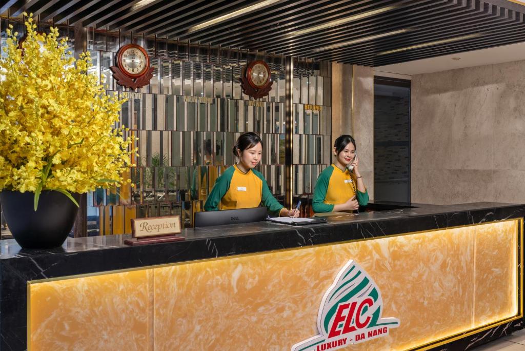 two women are standing at a counter in a restaurant at ELC Luxury Hotel Danang - An Thuong Walking Street in Da Nang