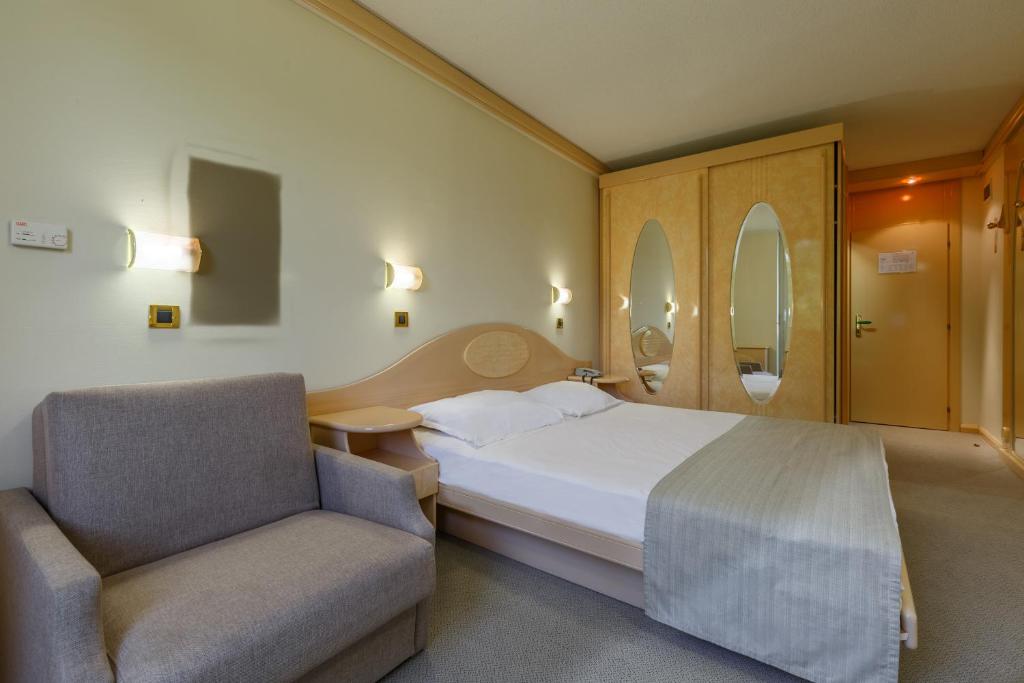 a hotel room with a bed and a chair at Hotel Istra Plava Laguna in Poreč