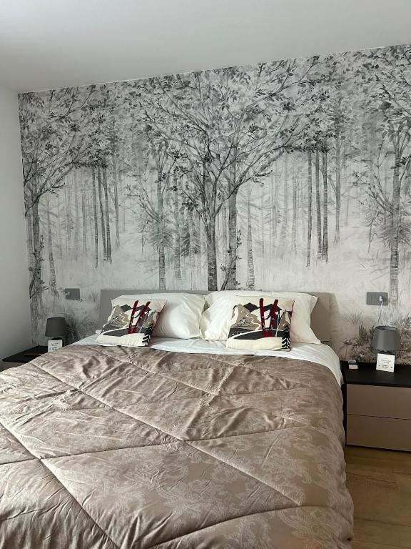a bedroom with a large bed with trees on the wall at Bormio365 Chalet in Valdisotto