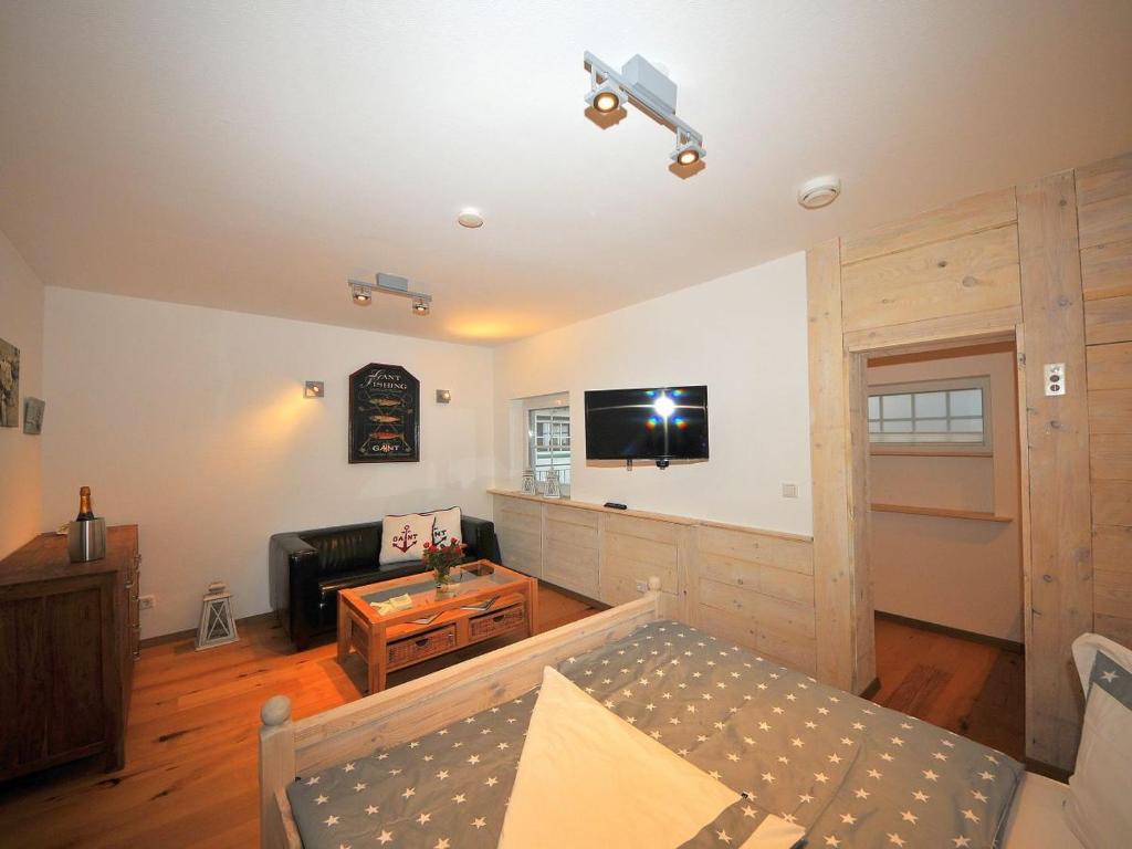 a living room with a couch and a tv on the wall at ENA Ferien Strandkiste in Juist