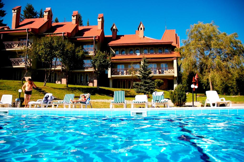 a hotel with a swimming pool in front of a building at Perlyna Karpat in Slavske