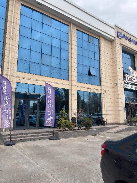 ein Gebäude mit zwei violetten Schildern davor in der Unterkunft AKS Hotel in Taschkent