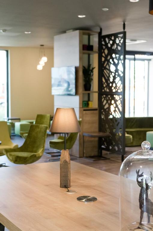 a lamp on a table in a room with green chairs at Super 8 by Wyndham Munich City North in Munich