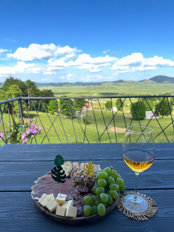 a plate of cheese and a glass of wine on a table at Monte zone in Žabljak
