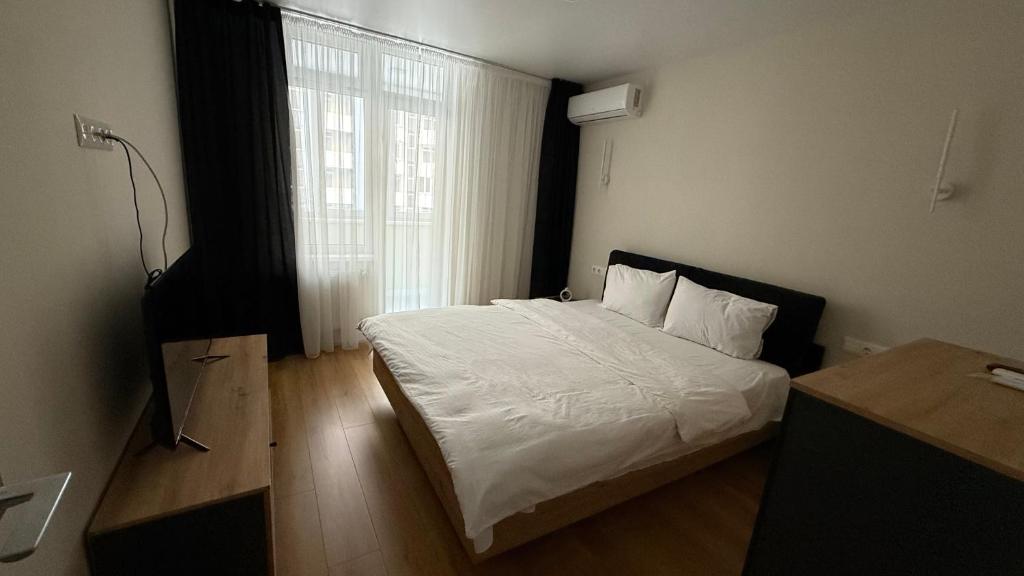 um quarto com uma cama com lençóis brancos e uma janela em Soft Loft ЖК Київський em Ternopil