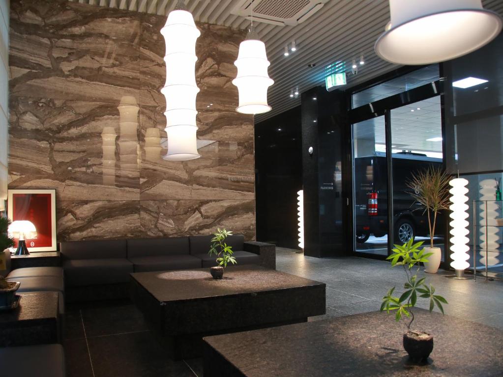 Un vestíbulo con una pared de piedra con plantas en macetas y luces. en 구미 더혜밀호텔, en Gumi