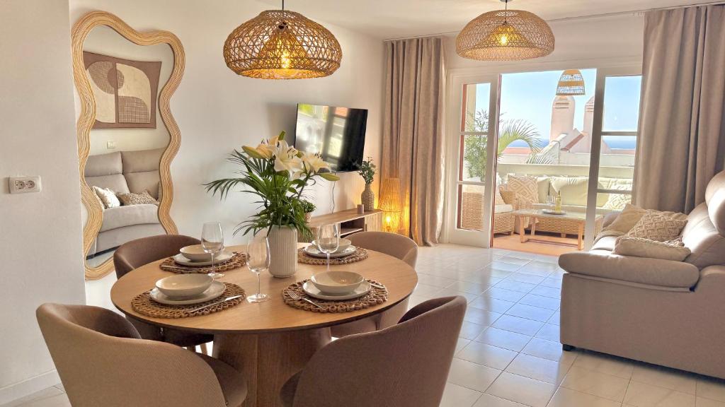ein Wohnzimmer mit einem Holztisch und Stühlen in der Unterkunft CASA BLANCA Port Royale - heated pool, ocean view, fibre net in Los Cristianos