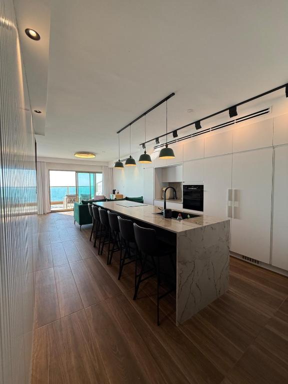 a kitchen with a bar with chairs and a sink at Stylish Penthouse Beach Front in Ashkelon