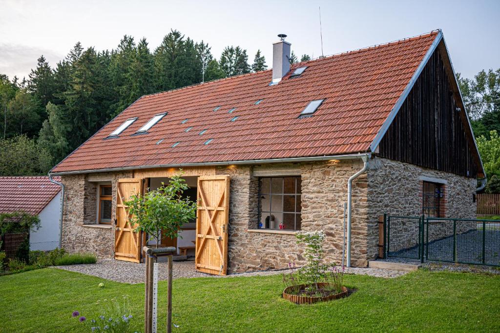 una pequeña casa de piedra con techo rojo en Stodola 63, en Pacov