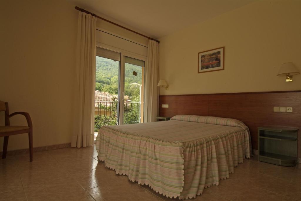 a bedroom with a bed and a large window at Fonda Finet in Sant Felíu de Pallarols