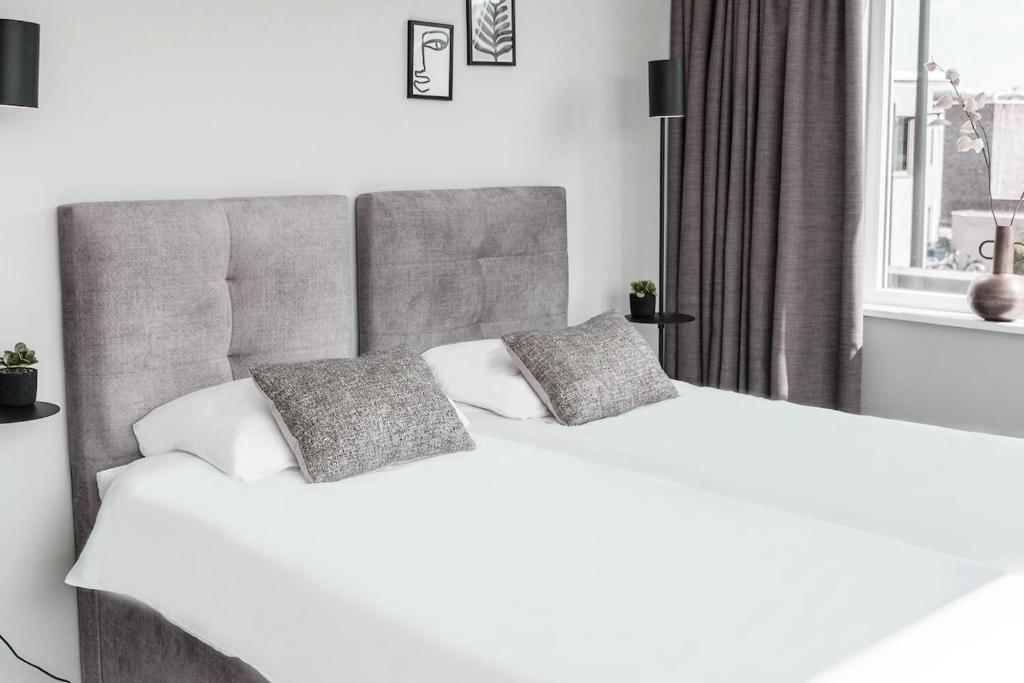 2 camas blancas en un dormitorio con ventana en Spacious Suite w AC, City Center, en Geertruidenberg