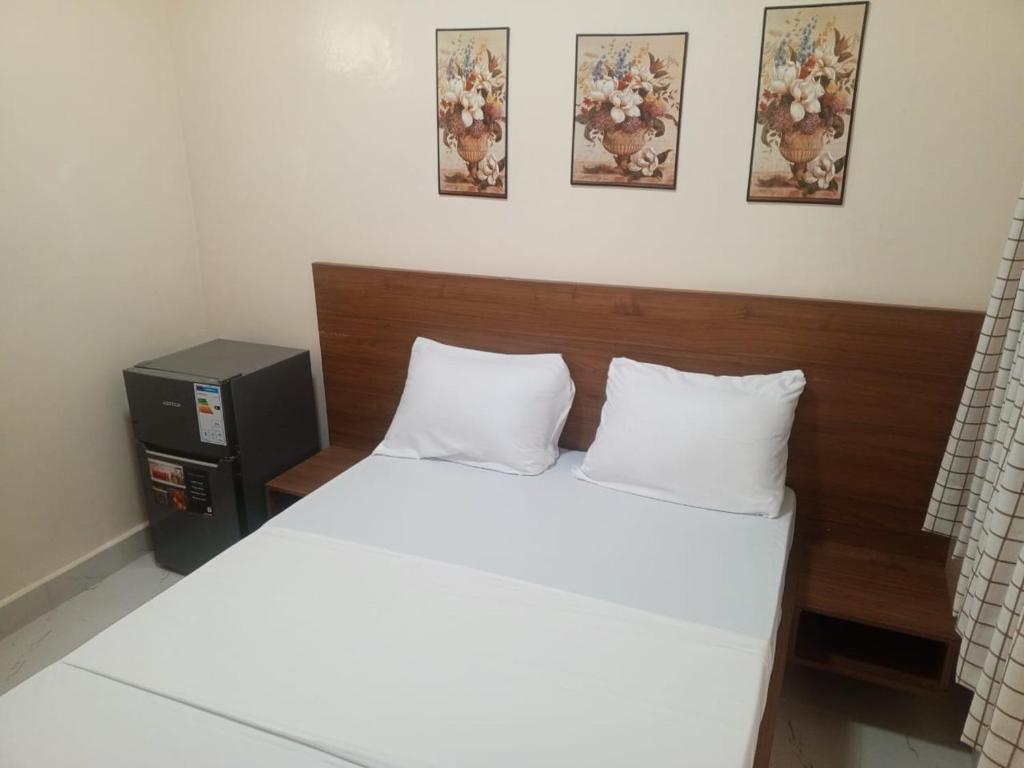 ein Bett mit weißen Laken und einem hölzernen Kopfteil in der Unterkunft Résidence Keur Mame Seye 4 in Dakar