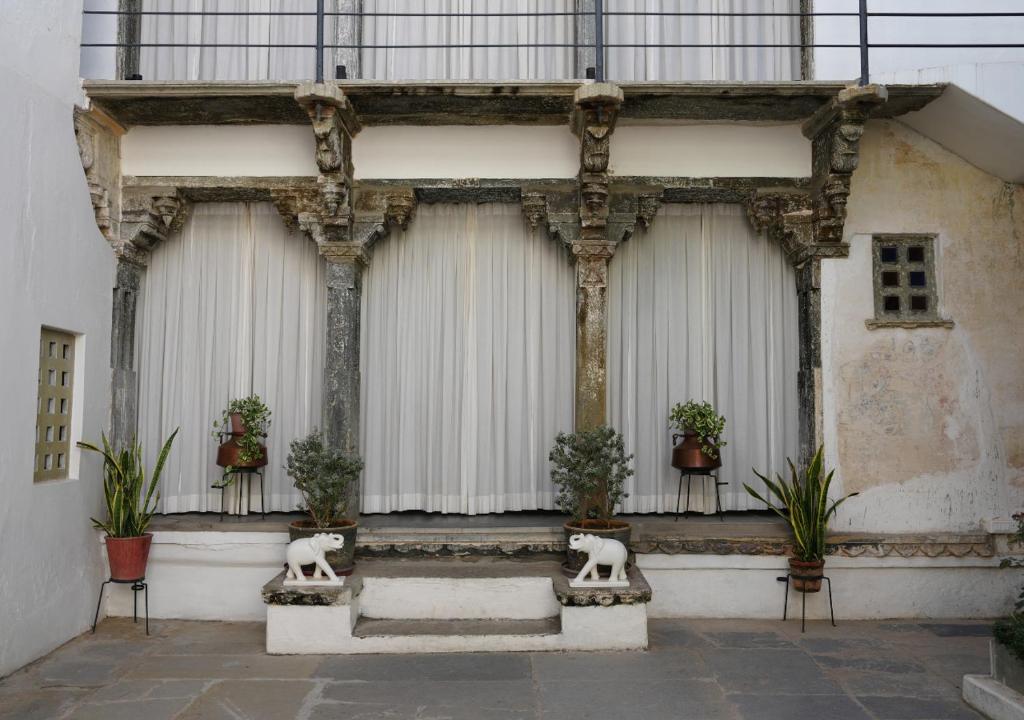 un edificio con tende bianche e piante in vaso di Little Garden Guest House a Udaipur