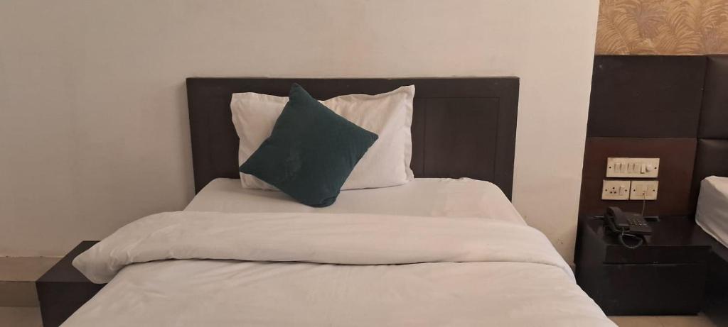 Hotel Anmol Palace في غازي آباد: سرير عليه وسادة خضراء